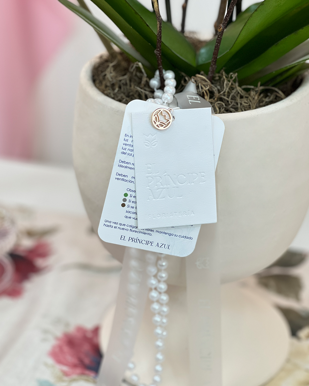 ORQUÍDEA PERLITE es un arreglo de orquídea en base artesanal, con detalles dorados y perlas, que rinde homenaje a mamá con elegancia, equilibrio y sofisticación eterna.
