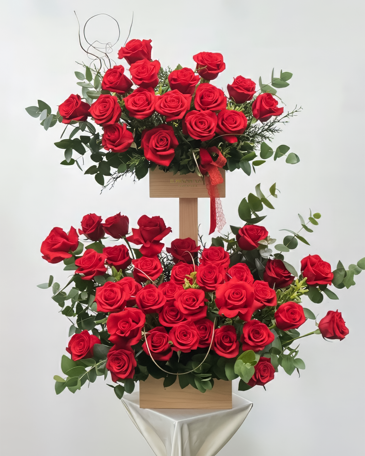 QUEEN 100 ROSAS es un exuberante arreglo de rosas rojas en dos niveles, diseñado para honrar con grandeza a mamá. Un tributo floral tan inolvidable como ella.