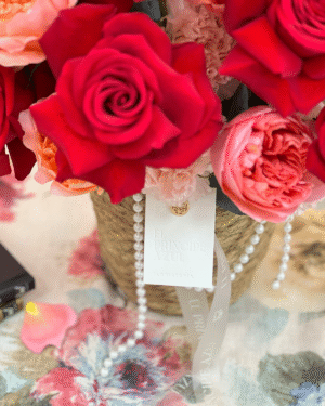 RUBIENNE es un arreglo de rosas para el Día de las Madres que fusiona la fuerza del rojo con la ternura del rosa, en una delicada cesta de mimbre adornada con perlas. Cada flor, cada detalle, celebra con gracia la belleza de su amor.