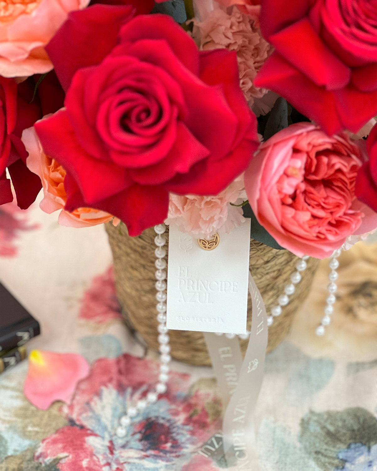 RUBIENNE es un arreglo de rosas para el Día de las Madres que fusiona la fuerza del rojo con la ternura del rosa, en una delicada cesta de mimbre adornada con perlas. Cada flor, cada detalle, celebra con gracia la belleza de su amor.