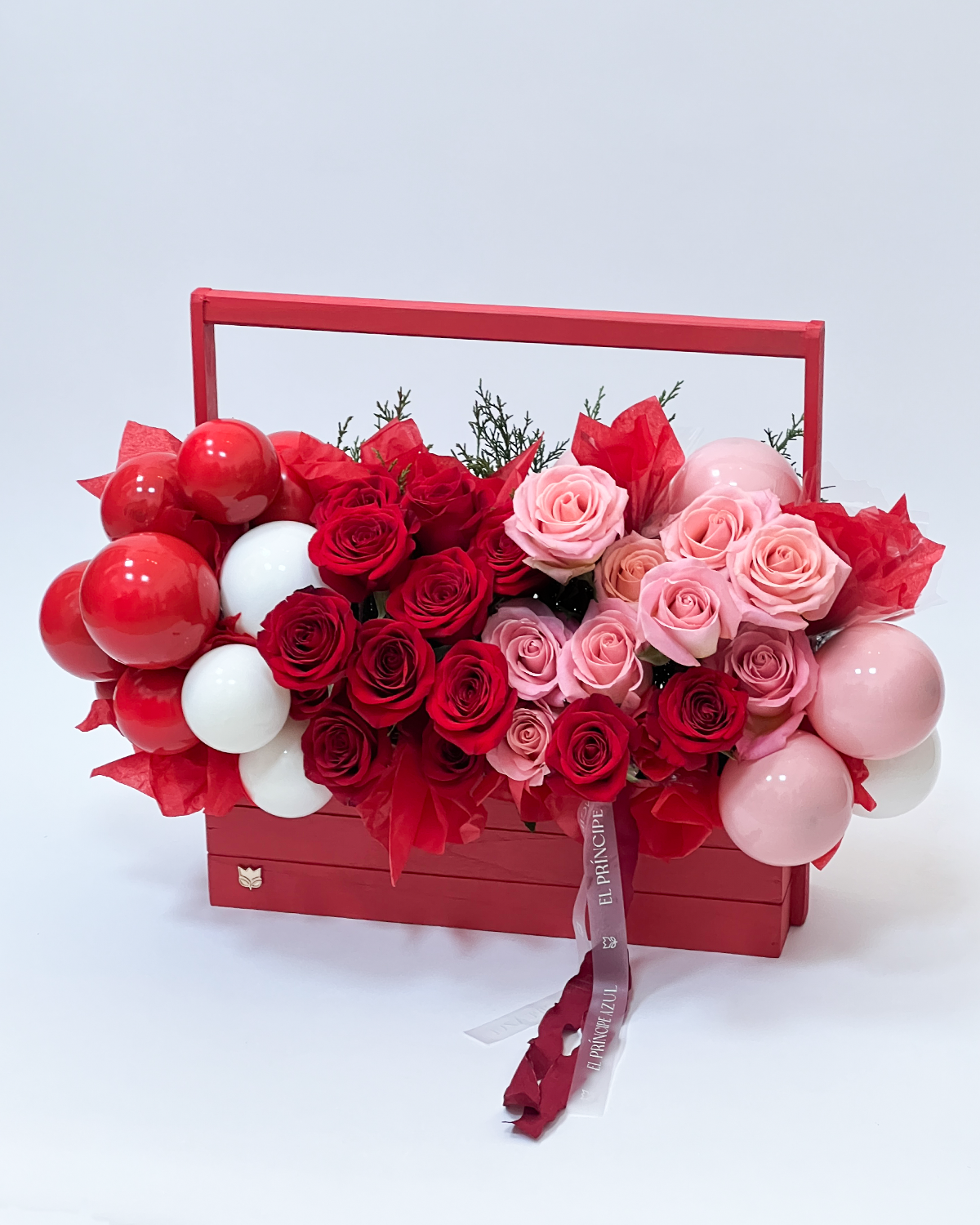 INCANTO une rosas rojas y rosadas con globos delicados en una elegante caja de madera, creando una experiencia romántica que eleva el amor y celebra su magia, con el sello inconfundible de El Príncipe Azul.